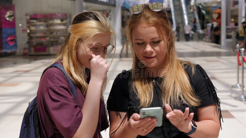 Una mujer adulta con una adolescente en un centro comercial con un teléfono en sus manos. almacen de metraje de vídeo
