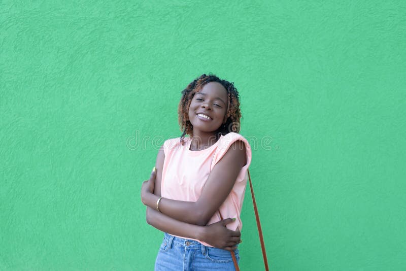 Una mujer afroamericana sonriente y feliz con un fondo verde. emociones positivas. romance imagen de archivo