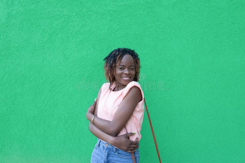 Una mujer afroamericana sonriente y feliz con un fondo verde. emociones positivas. romance imagen de archivo libre de regalías