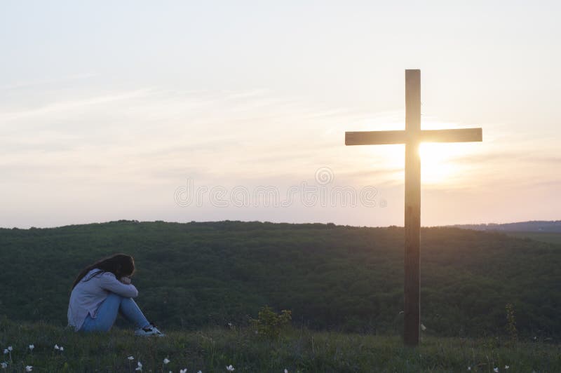 Una mujer arrodillada. cerca de la cruz. oración del arrepentimiento. fe cristiana.
