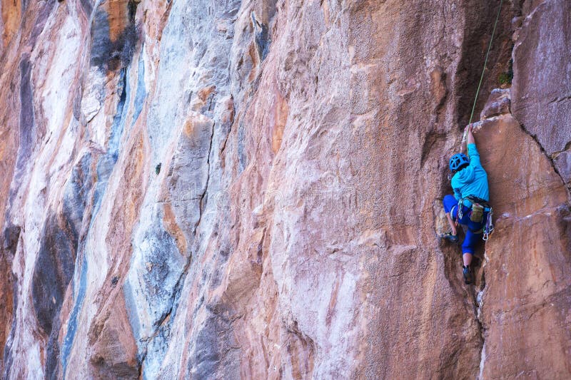 Una mujer con casco trepa una hermosa roca azul imagenes de archivo