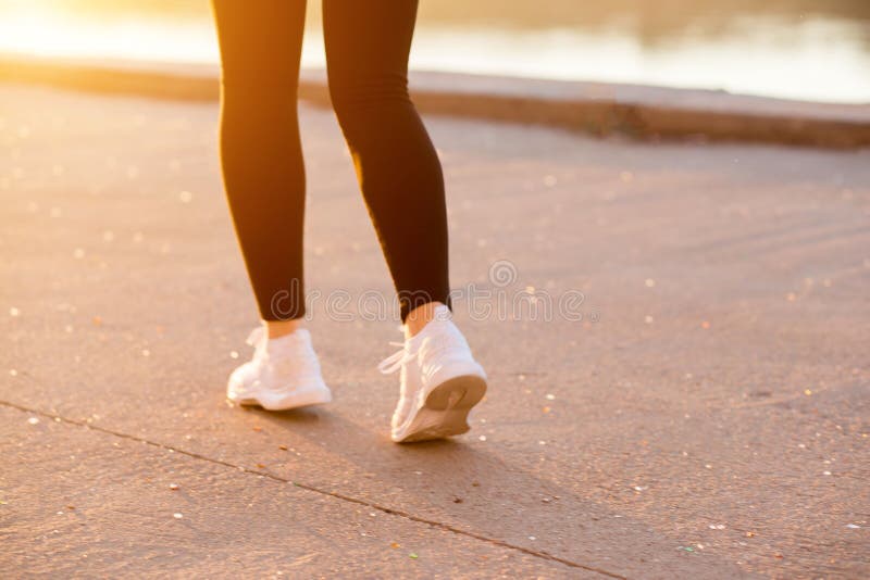 Una mujer con una figura delgada, muscular corre alrededor en ropa negra de los deportes y zapatillas de deporte blancas en natur imagen de archivo libre de regalías Una mujer con una figura delgada, muscular corre alrededor en ropa negra de los deportes y zapatillas de deporte blancas en natur imagen de archivo libre de regalías