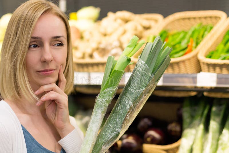 Una mujer con las verduras piensa en la tienda imágenes de archivo libres de regalías Una mujer con las verduras piensa en la tienda imágenes de archivo libres de regalías