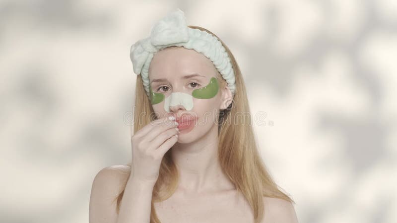 Una mujer con manchas bajo los ojos en los labios con un parche de cabezas negras en la nariz sobre un fondo amarillo con metrajes