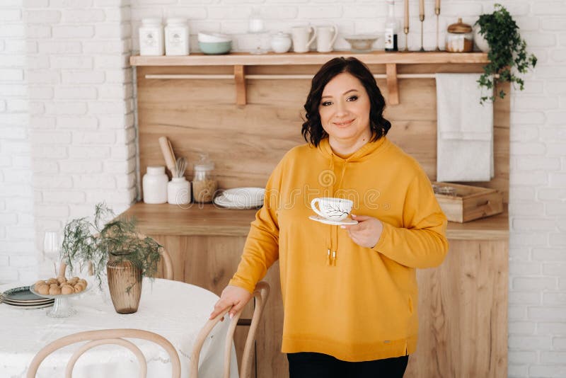 Mujer Con Una Sudadera Naranja Bebe Café La Cocina De Casa Foto de archivo - Imagen de chaqueta, feliz: