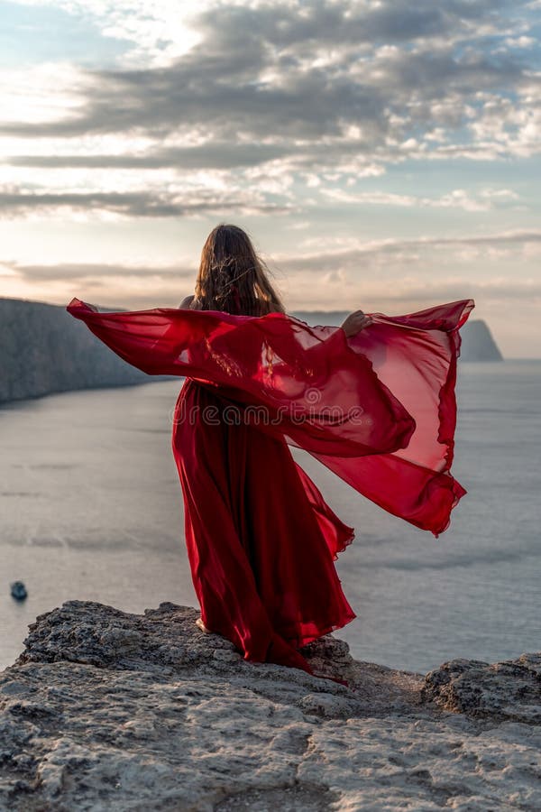 Una Mujer Con Un Vestido Rojo Se Alza Un Cielo Tormentoso Con Su Vestido Revoloteando El Tejido Volando En El Viento. Foto de - Imagen de vestido, modelo: 253157150