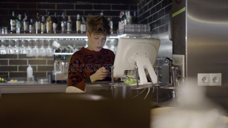 Una mujer de cadena corta usa computadora y teléfono en el bar del restaurante slomo