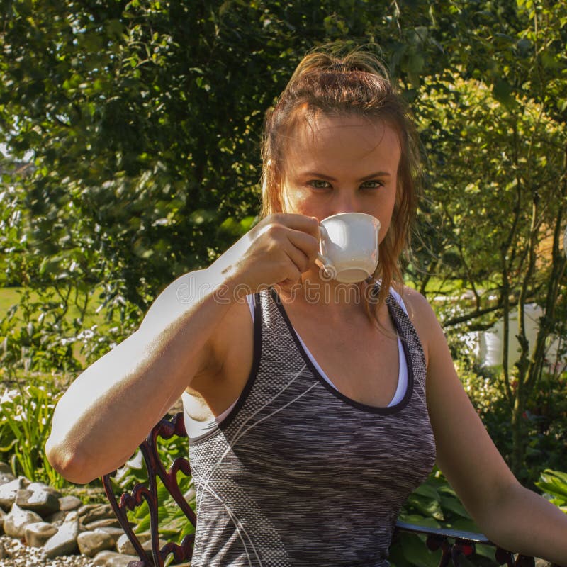 Una mujer deportiva joven con una taza de café, día soleado, parque fotos de archivo Una mujer deportiva joven con una taza de café, día soleado, parque fotos de archivo