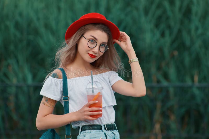 Una mujer elegante joven que tiene una bebida de restauración mientras que camina foto de archivo libre de regalías