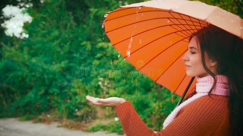 Una mujer en la lluvia toca las caídas de un paraguas. mal tiempo almacen de video