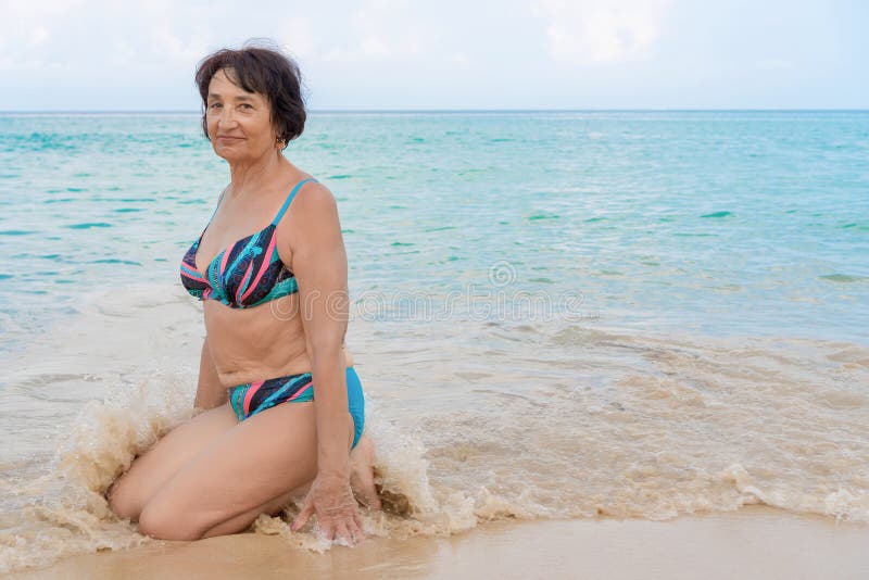 Una mujer en un bañador que mira la cámara y y la sonrisa fotos de archivo Una mujer en un bañador que mira la cámara y y la sonrisa fotos de archivo