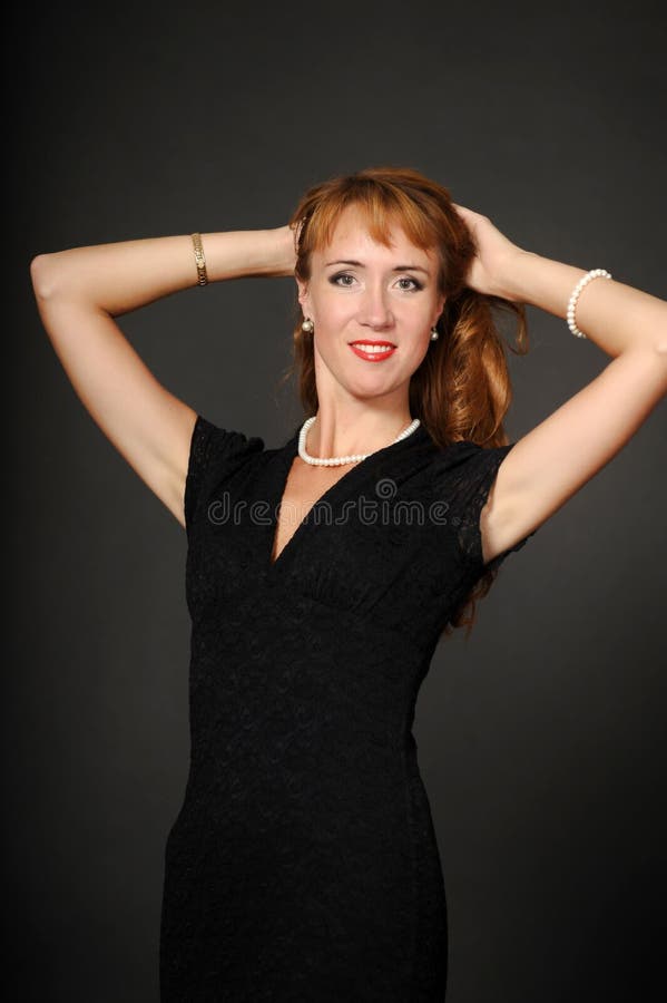 Una mujer en un vestido negro que se sostiene el pelo fotografía de archivo libre de regalías Una mujer en un vestido negro que se sostiene el pelo fotografía de archivo libre de regalías