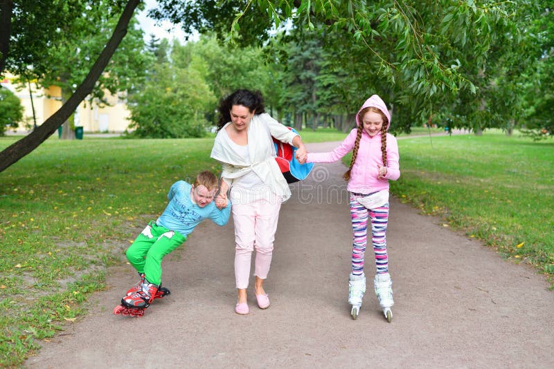 Una mujer enseña a dar los primeros pasos en patines infantiles fotos de archivo