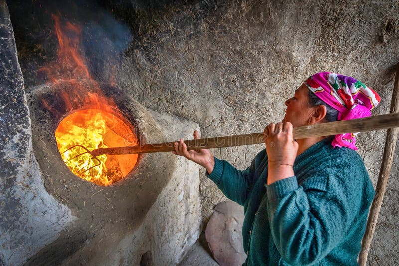 Una mujer está encendiendo un tandoor - un horno tradicional del Uzbek foto de archivo Una mujer está encendiendo un tandoor - un horno tradicional del Uzbek foto de archivo