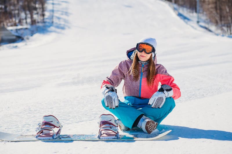 Una Mujer Hermosa En La Ropa Para Snowboard Que Se Sienta En La Pista Para La Snowboard de archivo - Imagen de activo, nieve: 131745345