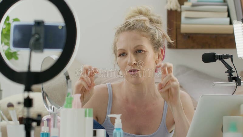 Una mujer influyente blogger sonriente grabando un video tutorial en una cámara de smartphone explica qué hacer para aplicar cosmé metrajes