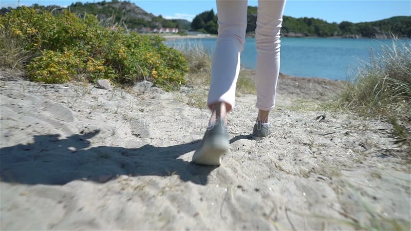 Una mujer joven camina entre las dunas hacia el mar