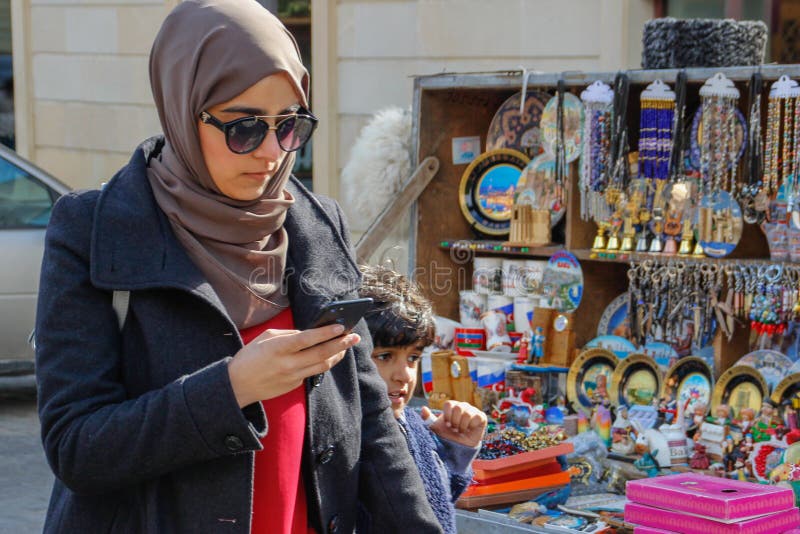 Una mujer joven de Aresbaidan en paseos del hijab y de los vidrios a lo largo de la calle de la ciudad vieja con los recuerdos az imagen de archivo Una mujer joven de Aresbaidan en paseos del hijab y de los vidrios a lo largo de la calle de la ciudad vieja con los recuerdos az imagen de archivo