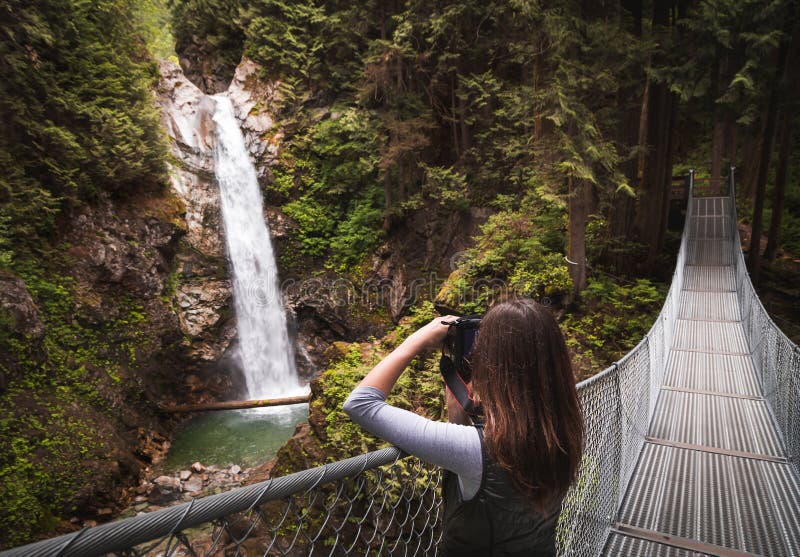 Una Mujer Joven En Puente Colgante Que Toma Una Foto De Una Imagen de archivo Imagen de belleza, verde: