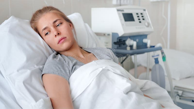 Una mujer joven enferma que miente en una cama de hospital y que espera a un doctor almacen de video