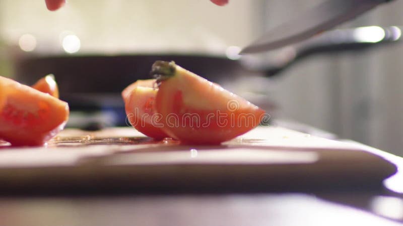 Una mujer joven está cocinando una ensalada en la cocina Ella corta el tomate jugoso rojo en muchos pequeños pedazos almacen de video