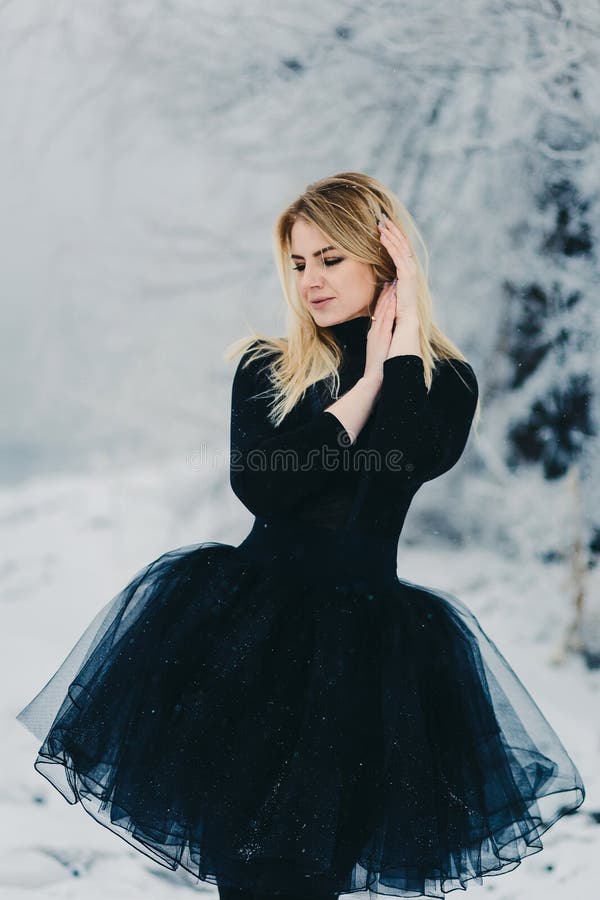 Una mujer joven hermosa en un vestido negro en bosque del invierno imágenes de archivo libres de regalías Una mujer joven hermosa en un vestido negro en bosque del invierno imágenes de archivo libres de regalías