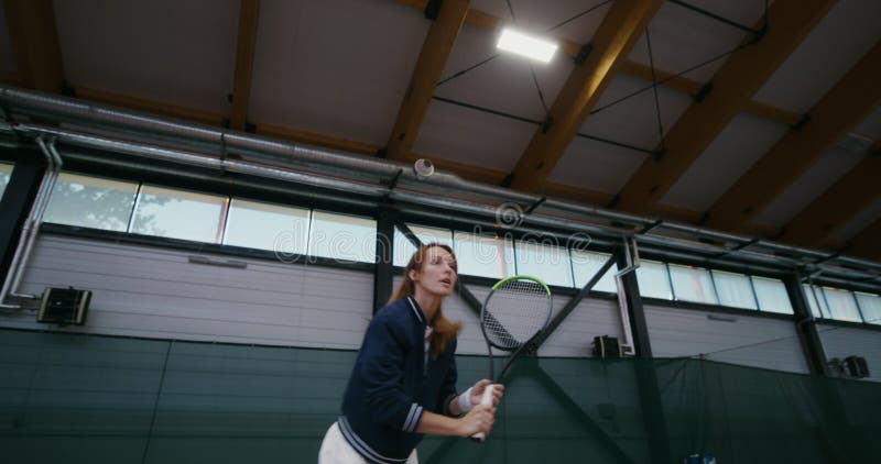 Una mujer juega al tenis profesional rebotando activamente con cada golpe de raqueta almacen de metraje de vídeo
