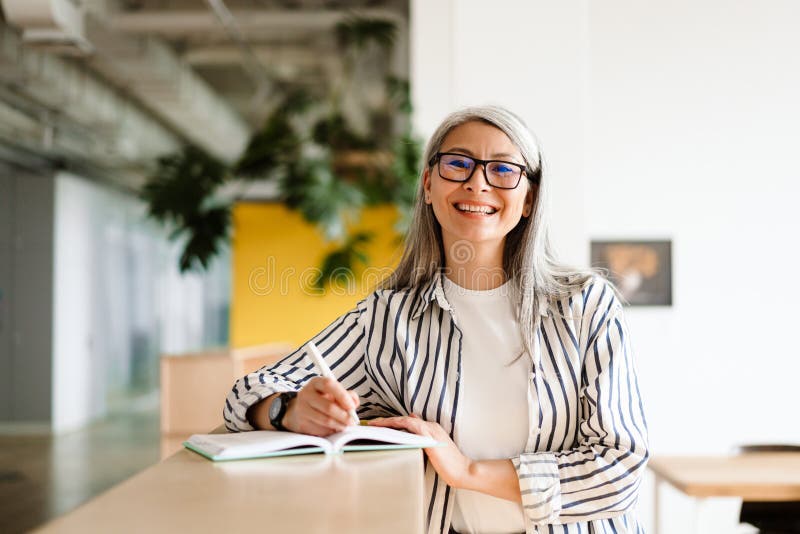 Una Mujer Madura De Pelo Blanco Alegre Sonriendo Mientras Escribe Notas Imagen De Archivo