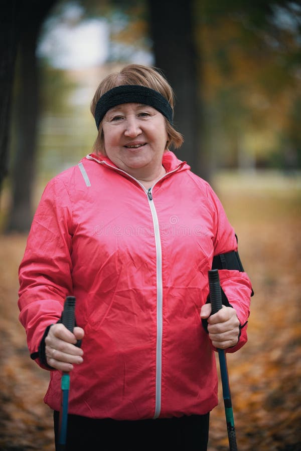 Una Mujer Mayor En Chaqueta Del Rosa Se Retirando En Un Parque Con Los Palillos Para Caminar Nórdico Foto de archivo Imagen de mayor, bosque: 127571152