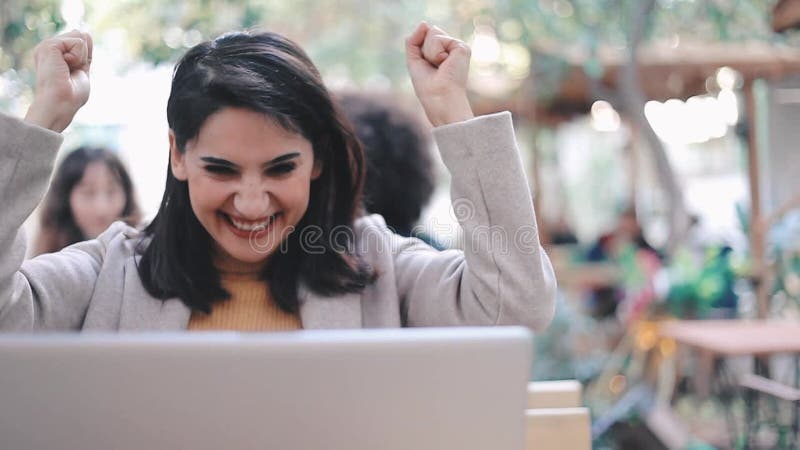 Una mujer muy joven usa una computadora en el jardín y recibe buenas noticias almacen de video