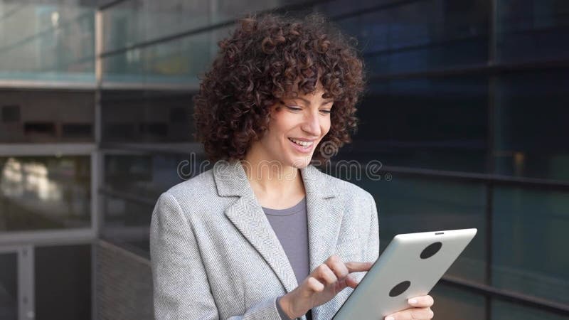 Una mujer profesional participa activamente en un entorno empresarial moderno utilizando su dispositivo de tableta almacen de video