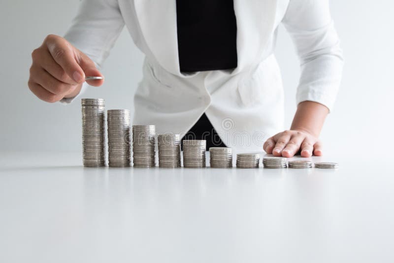 Una mujer que pone la moneda en monedas del crecimiento representa gráficamente en el traje blanco foto de archivo libre de regalías Una mujer que pone la moneda en monedas del crecimiento representa gráficamente en el traje blanco foto de archivo libre de regalías