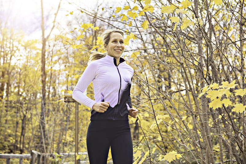 Una mujer rubia corriendo trotando en la naturaleza otoñal imagenes de archivo