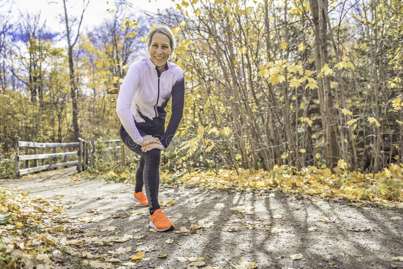 Una mujer rubia corriendo trotando en la naturaleza otoñal foto de archivo