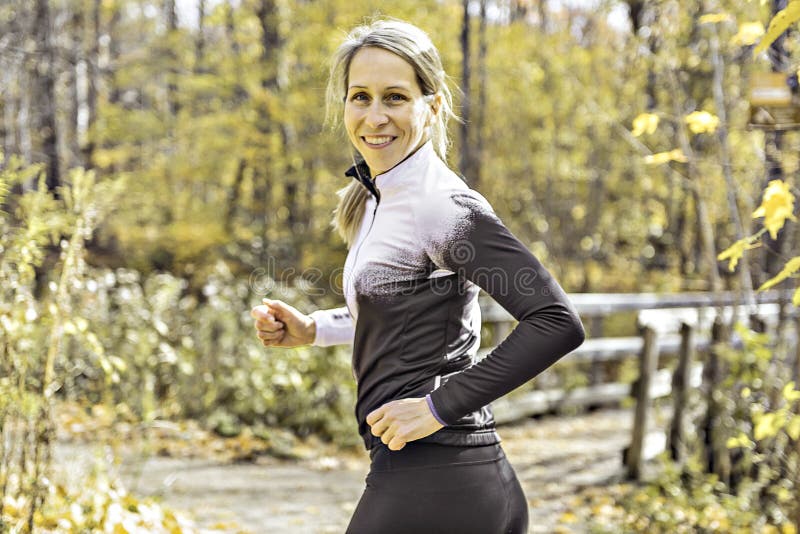 Una mujer rubia corriendo trotando en la naturaleza otoñal imagen de archivo libre de regalías