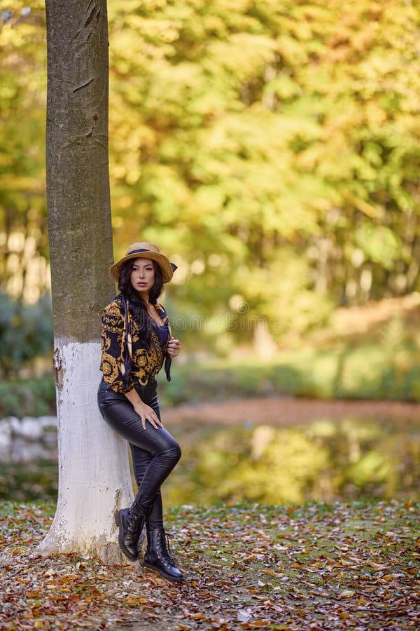Una mujer sentada junto a un lago inclinándose contra un árbol imágenes de archivo libres de regalías