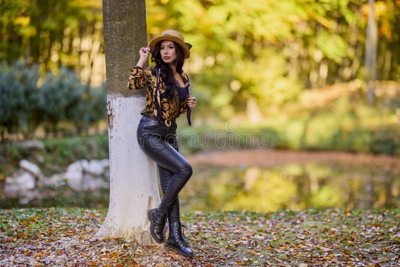 Una mujer sentada junto a un lago inclinándose contra un árbol fotografía de archivo