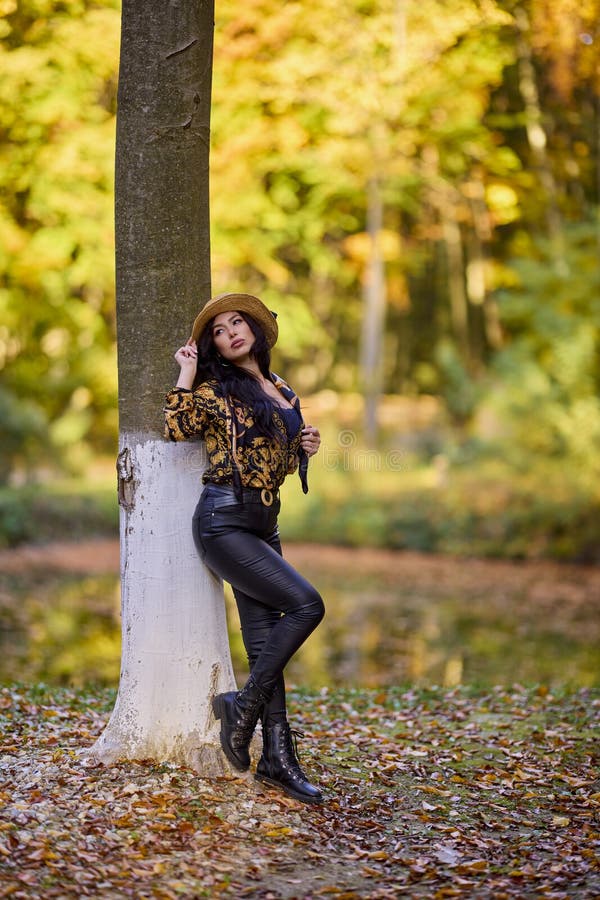 Una mujer sentada junto a un lago inclinándose contra un árbol imagen de archivo libre de regalías