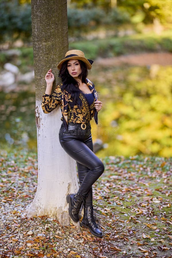 Una mujer sentada junto a un lago inclinándose contra un árbol imagen de archivo
