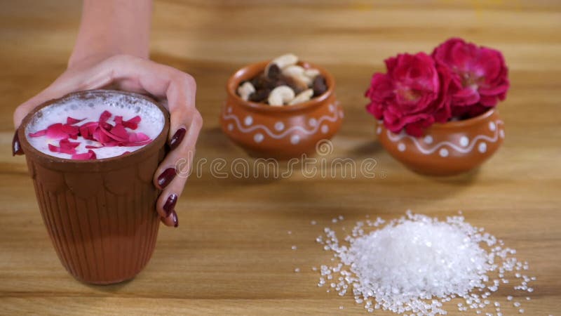 Una mujer sirviendo un vaso de chaas refrigeradas decoradas con pétalos de rosa