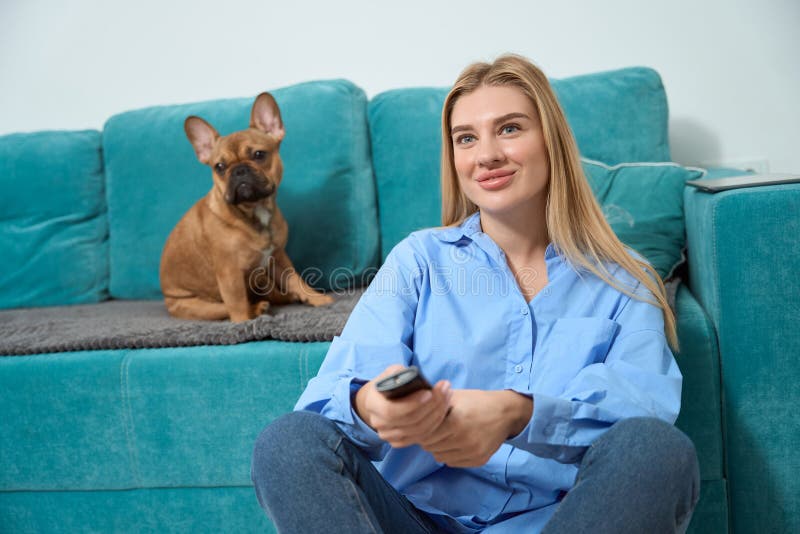 Una mujer sonriente y su amigo de cuatro patas mirando televisión imágenes de archivo libres de regalías