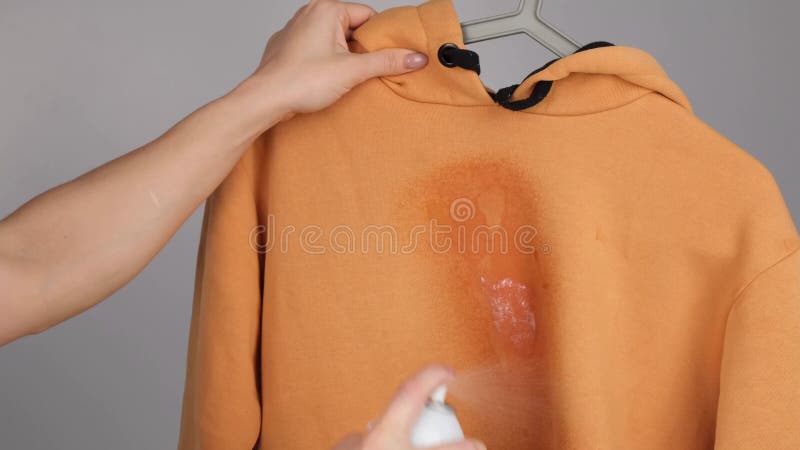 Una mujer usa un spray quitamanchas en una sudadera ocre almacen de video
