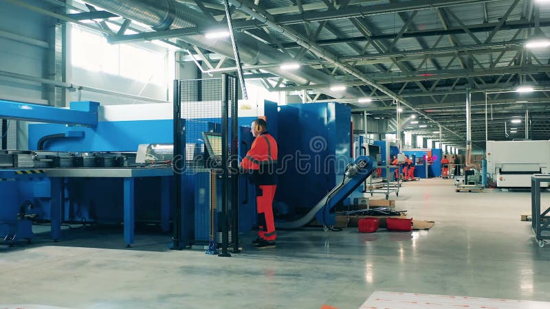 Una máquina de cizallar está siendo operada por un trabajador de fábrica. interior de la fábrica de producción industrial.