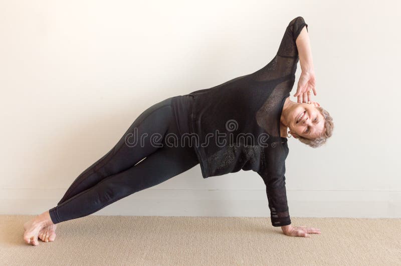 Una más vieja mujer que sonríe en postura del lado de la yoga fotos de archivo Una más vieja mujer que sonríe en postura del lado de la yoga fotos de archivo