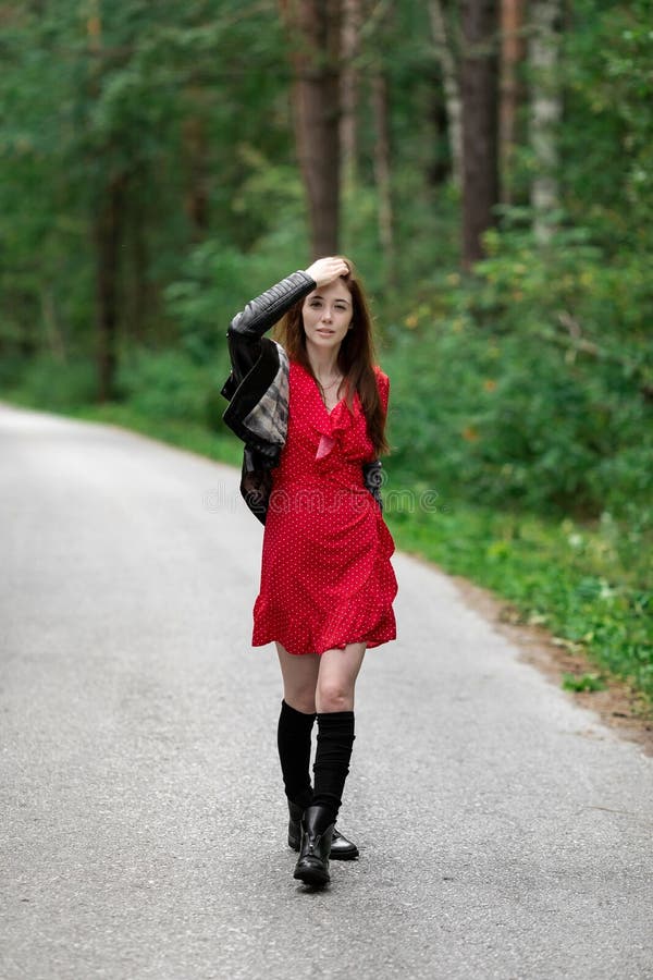 Una Niña Con Un Claro Vestido Rojo Y Ventilado Con Una Chaqueta De Cuero Al  Estilo De Una Roca En Un Camino Vacío En Un Bosque De Foto de archivo -  Imagen