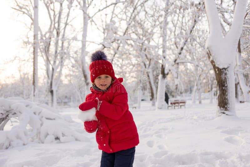 Una Niña De 6 Años Sola Imita Una Chaqueta Roja Y Un Sombrero De En Invierno Se Para En El Parque Y Arroja Foto de archivo - Imagen de risa, cabrito: 211676360