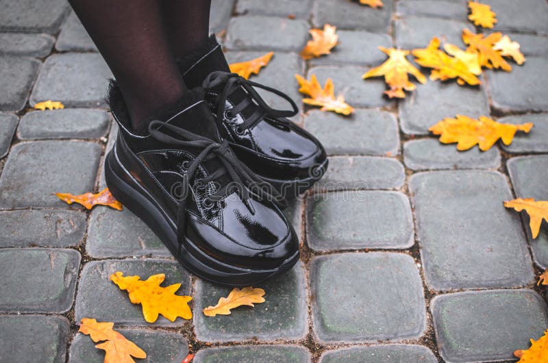 Niña Se Pone En Un Parque Con Zapatos Cálidos Brillantes Negros En Una Con En El Centro De La Ciudad Foto de archivo - Imagen de pies, fondo: 163870736