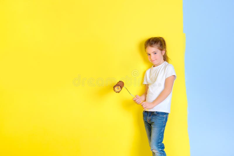 Una niña con un rodillo para pintar en sus manos imagenes de archivo Una niña con un rodillo para pintar en sus manos imagenes de archivo