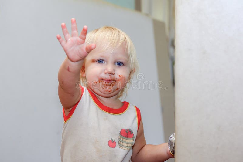 Una niña contrariado con la cara sucia de chocolate tira de la mano hacia delante que se lavará