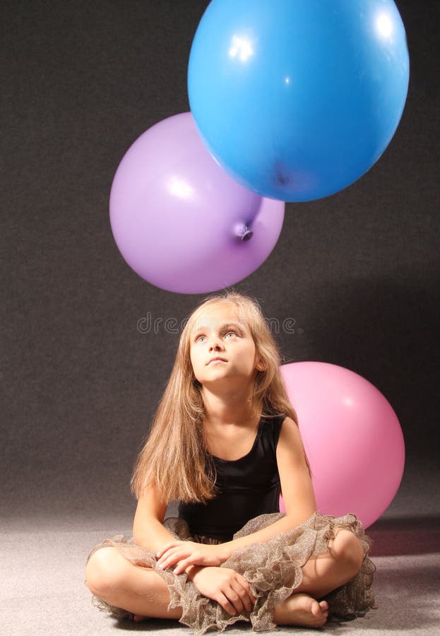 Una niña hermosa en un vestido negro se está sentando en el piso imagen de archivo libre de regalías Una niña hermosa en un vestido negro se está sentando en el piso imagen de archivo libre de regalías